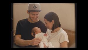 A family shares an intimate moment with their newborn baby in a casual home setting.