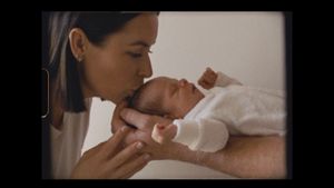 An intimate moment between caregiver and newborn baby dressed in white.