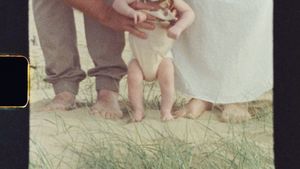 Close-up of bare feet on sand with gentle waves in the background.