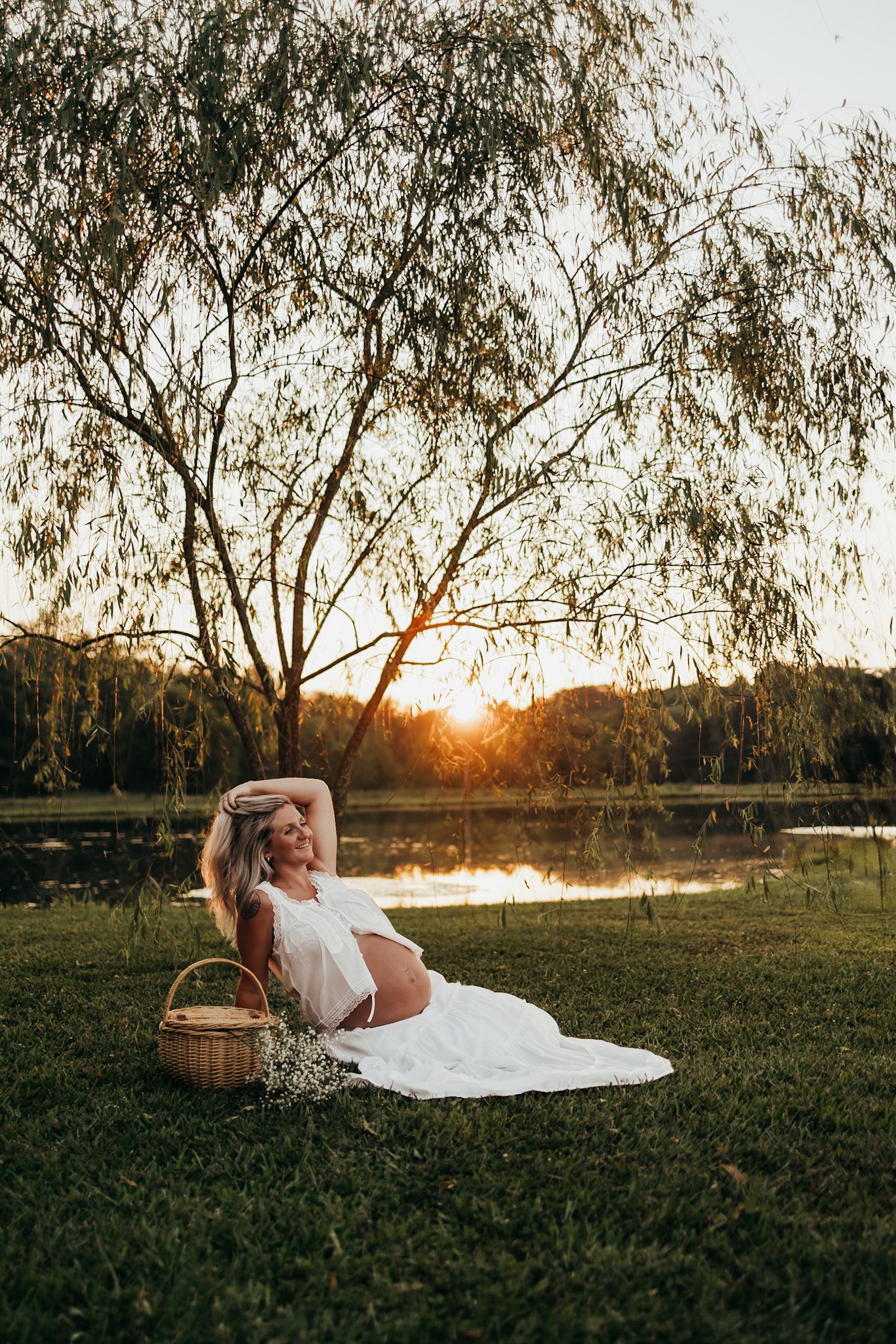 pregnant mom is sitting on a picnic blanket posing her growing belly