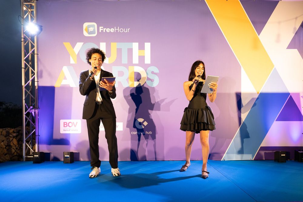 Illuminated stage backdrop with colorful geometric patterns and FreeHour logo at awards ceremony.