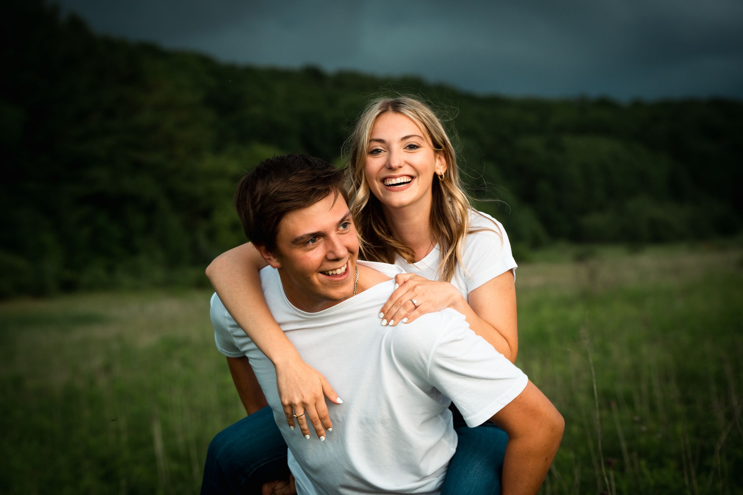 A couple shares intimate moments in a grassy field during a romantic outdoor photo session.