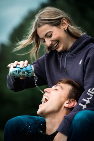 A sequence of photos showing someone pouring a can of energy drink into another person's mouth in a playful manner.