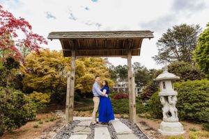 Couple shares intimate moment under wooden pergola in Japanese garden with stone lantern.