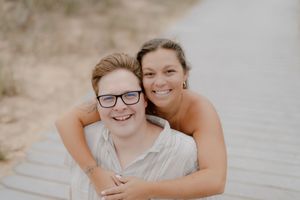 A happy couple embraces and smiles while posing for outdoor engagement photos.