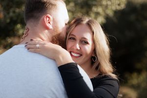A tender moment between a smiling couple against a natural outdoor setting.