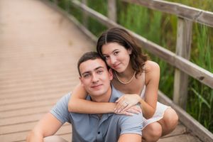 Couple sitting together on wooden stairs outdoors in a romantic setting during golden hour.