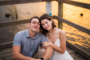 Couple sharing romantic moments during golden hour beach photoshoot while sitting on wooden steps.