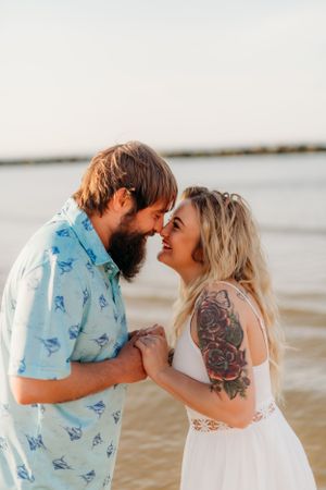 A romantic beach photo of a couple sharing an intimate moment at sunset.