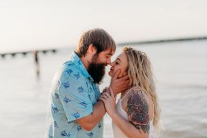 An affectionate couple shares a tender moment on the beach at golden hour.