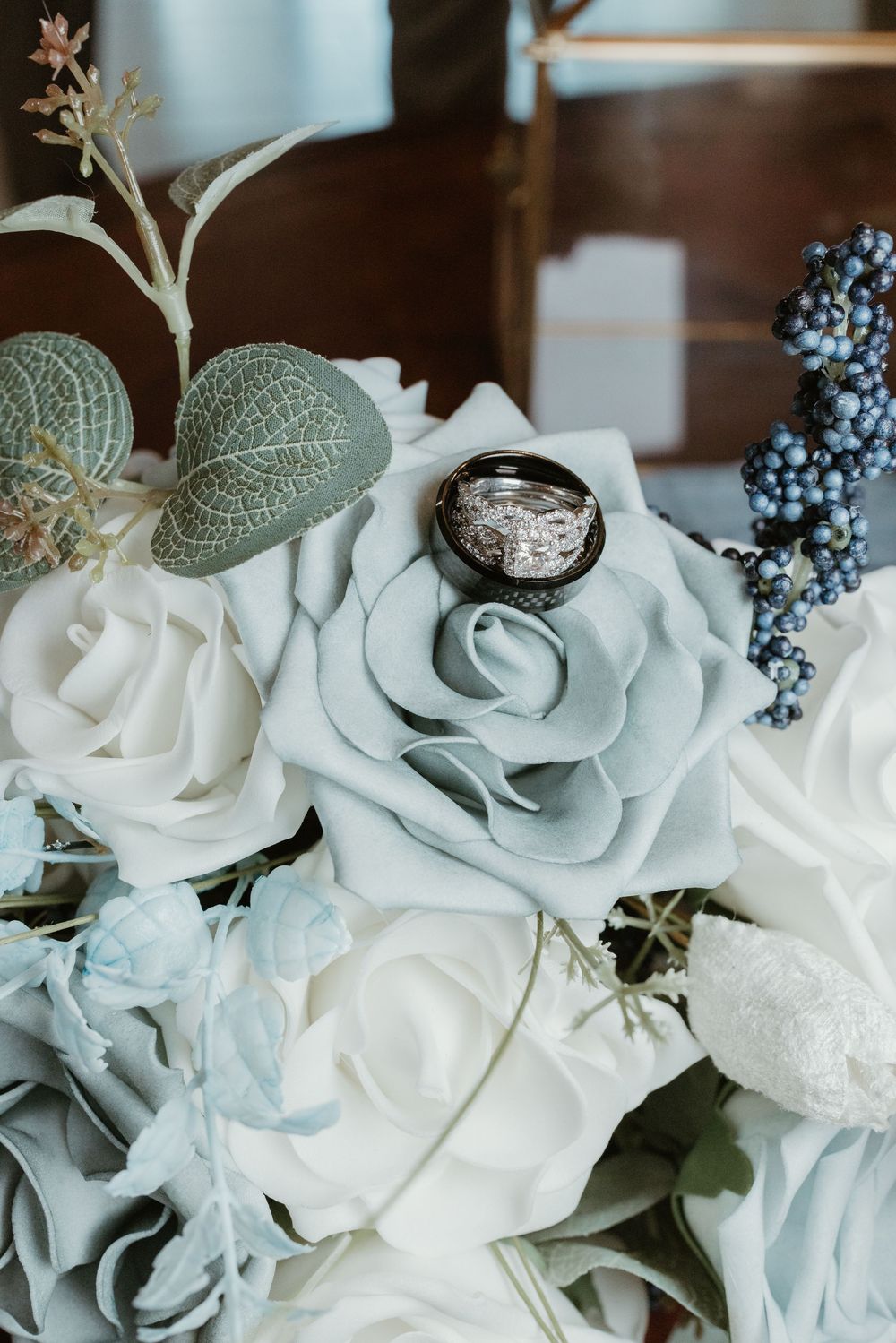 Delicate arrangement of white and pale blue roses with silver accents.