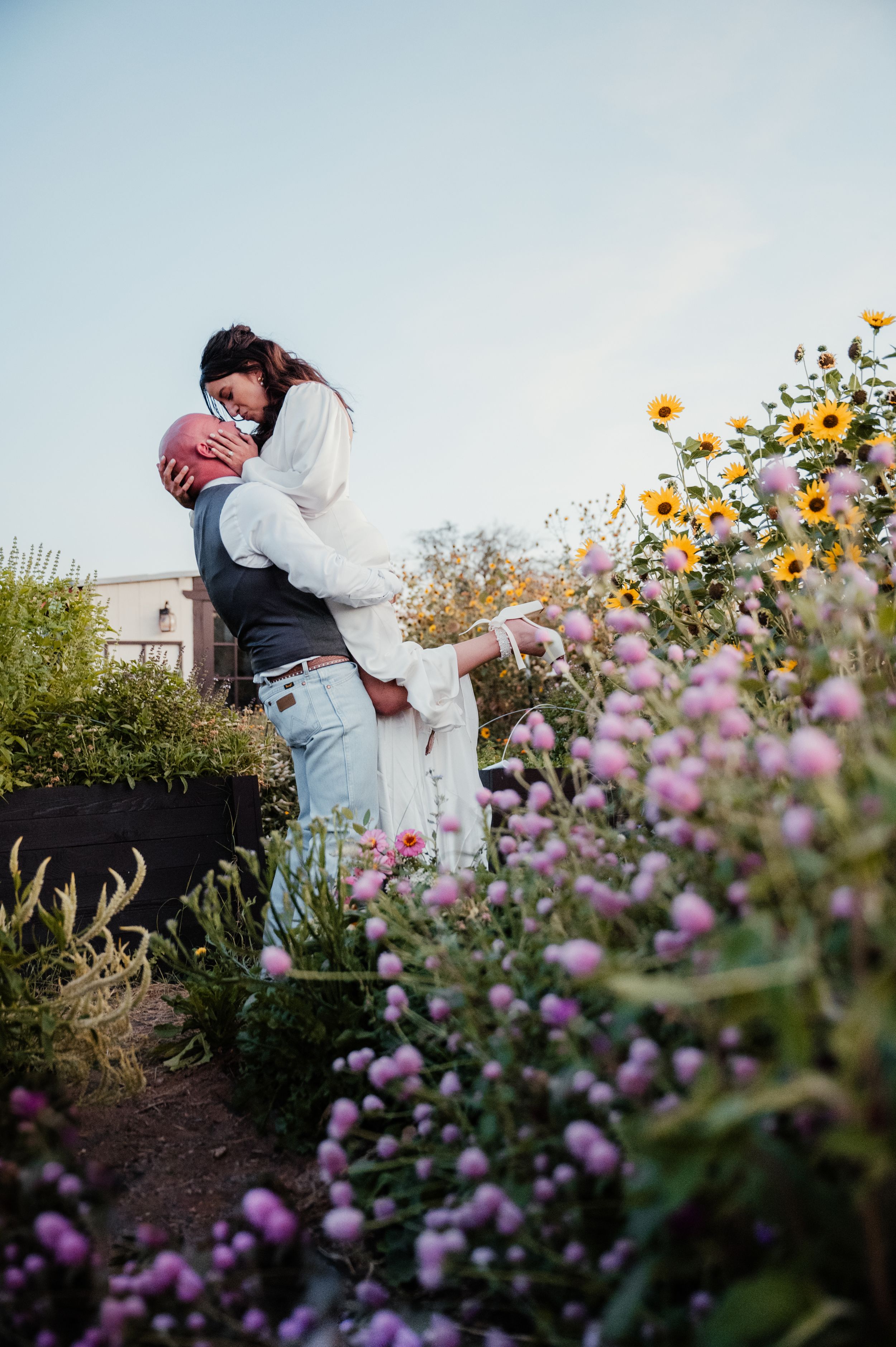 A romantic moment in a garden filled with purple and yellow flowers during golden hour.