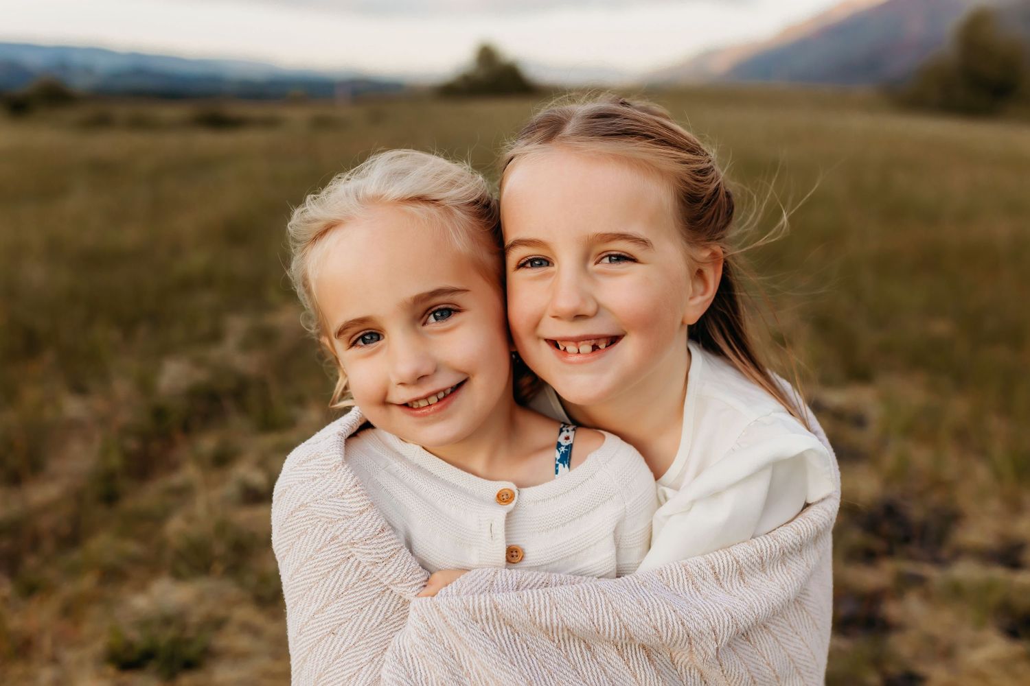 Two young sisters smile and embrace