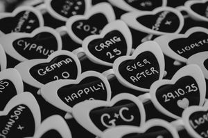 Black and white chalkboard hearts with handwritten text create a romantic pattern on a dark background.