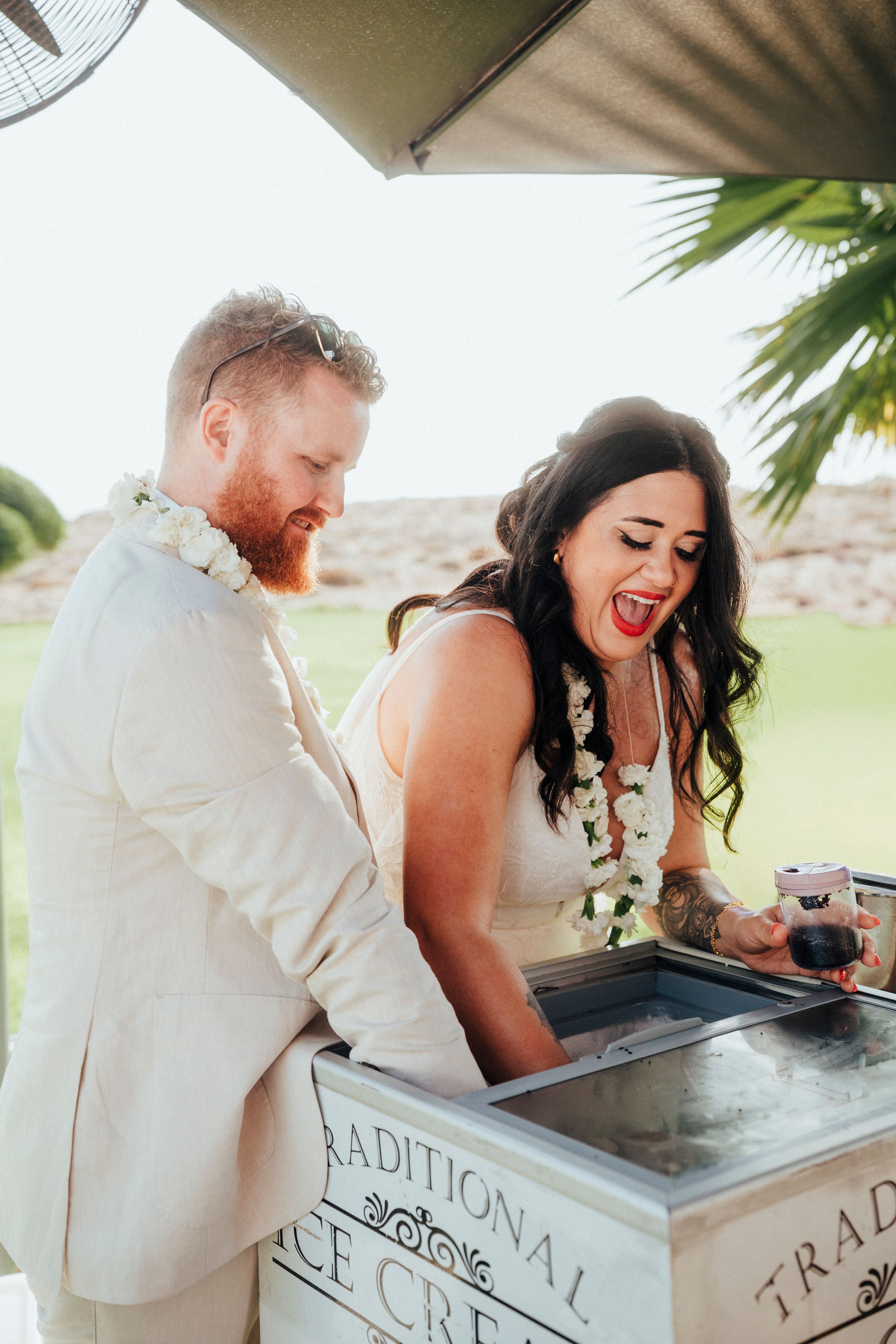 Couple shares a joyful moment while signing documents at an outdoor venue with palm trees in the background.