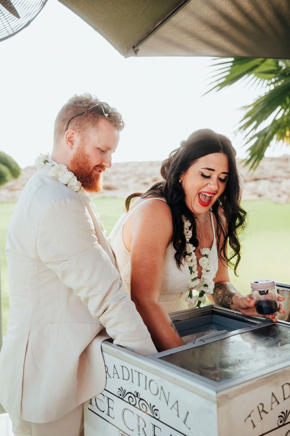 Couple shares a joyful moment while signing documents at an outdoor venue with palm trees in the background.