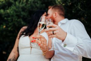 Couple toasting with champagne glasses in a romantic outdoor setting during a celebration event.