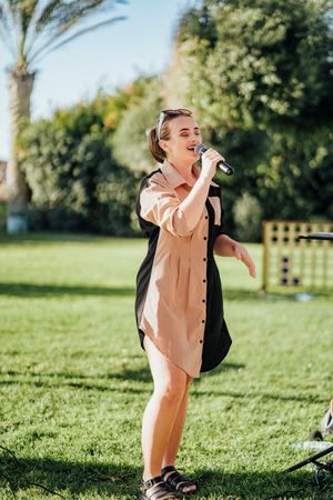A child in a peach-colored outfit plays and laughs joyfully while running on green grass in a sunny outdoor setting.