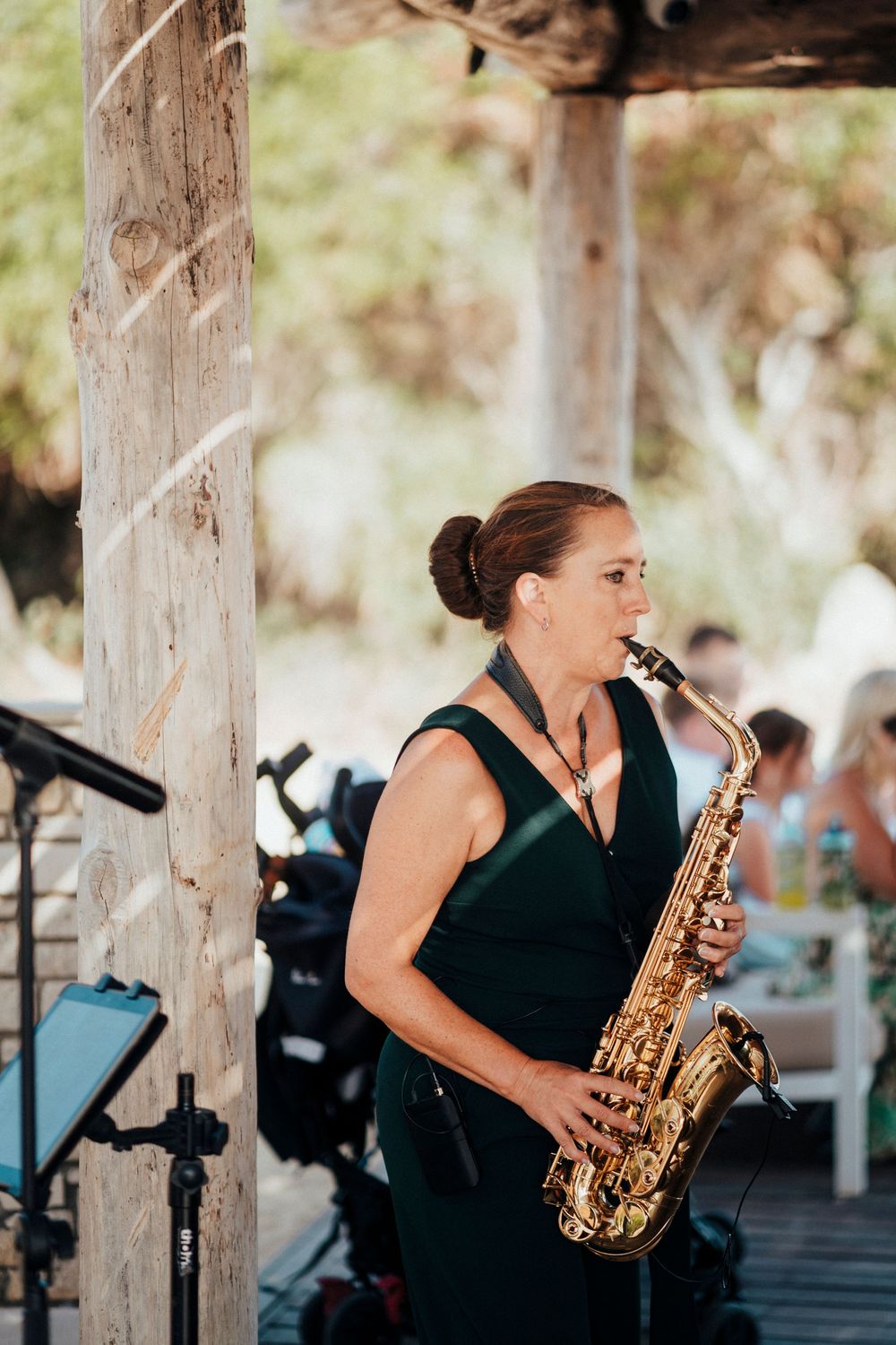 A musician performs on saxophone during an outdoor event while wearing an elegant black dress.