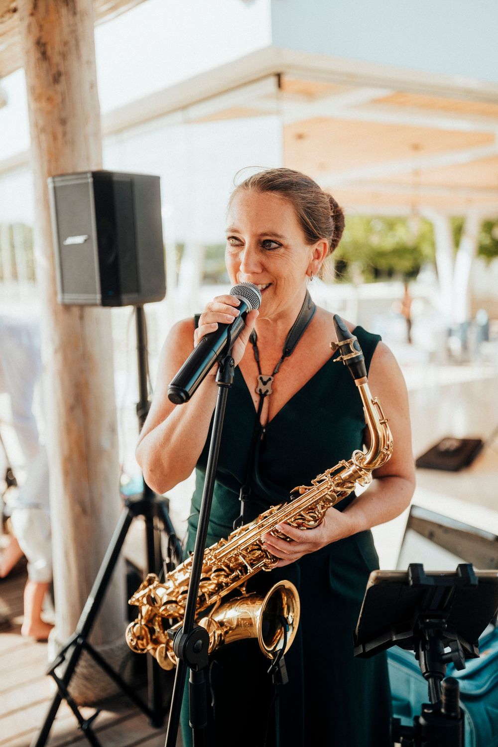 A musician performs with a saxophone at an outdoor venue, captured in a series of candid shots while singing into a microphone.