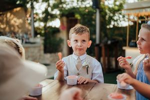 Children enjoy eating and drinking at an outdoor gathering in natural sunlight.