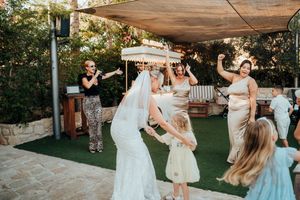 Wedding guests dance and celebrate together on an outdoor patio during a joyful reception celebration at sunset.