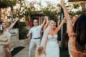 Wedding guests dancing and celebrating at an outdoor reception during golden hour.