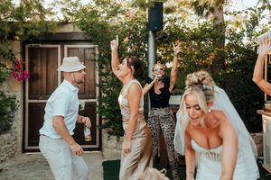 Wedding party guests dancing and celebrating outdoors at a garden reception during golden hour.
