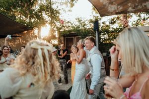 Outdoor wedding celebration with guests dancing and enjoying festivities at sunset.