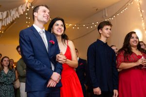 Wedding guests enjoying themselves at an indoor reception with string lights.