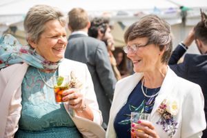 Two guests share drinks and laughter at an outdoor celebration.