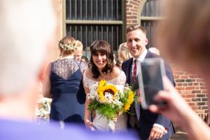 Wedding celebration with bright sunflowers against brick building backdrop.