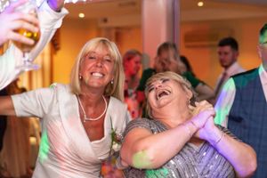 Dancing wedding guests share laughter during reception party celebrations.