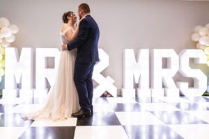 A romantic moment in front of illuminated MR & MRS letters at a wedding reception.