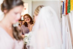 Wedding preparation scene reflected in mirror with bridal party getting ready.