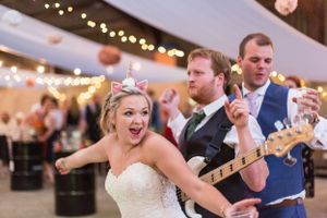 A celebratory moment at a wedding reception with a guitar and festive string lights in the background.