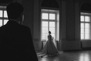 Sulhanen katsoo morsianta suuressa juhlasalissa, intiimi first look -hetki – hääkuvaus Helsinki
