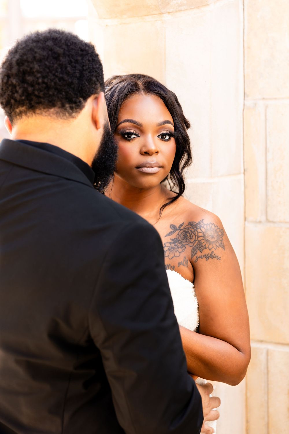 Intimate wedding portraits captured under stone archway with natural lighting.