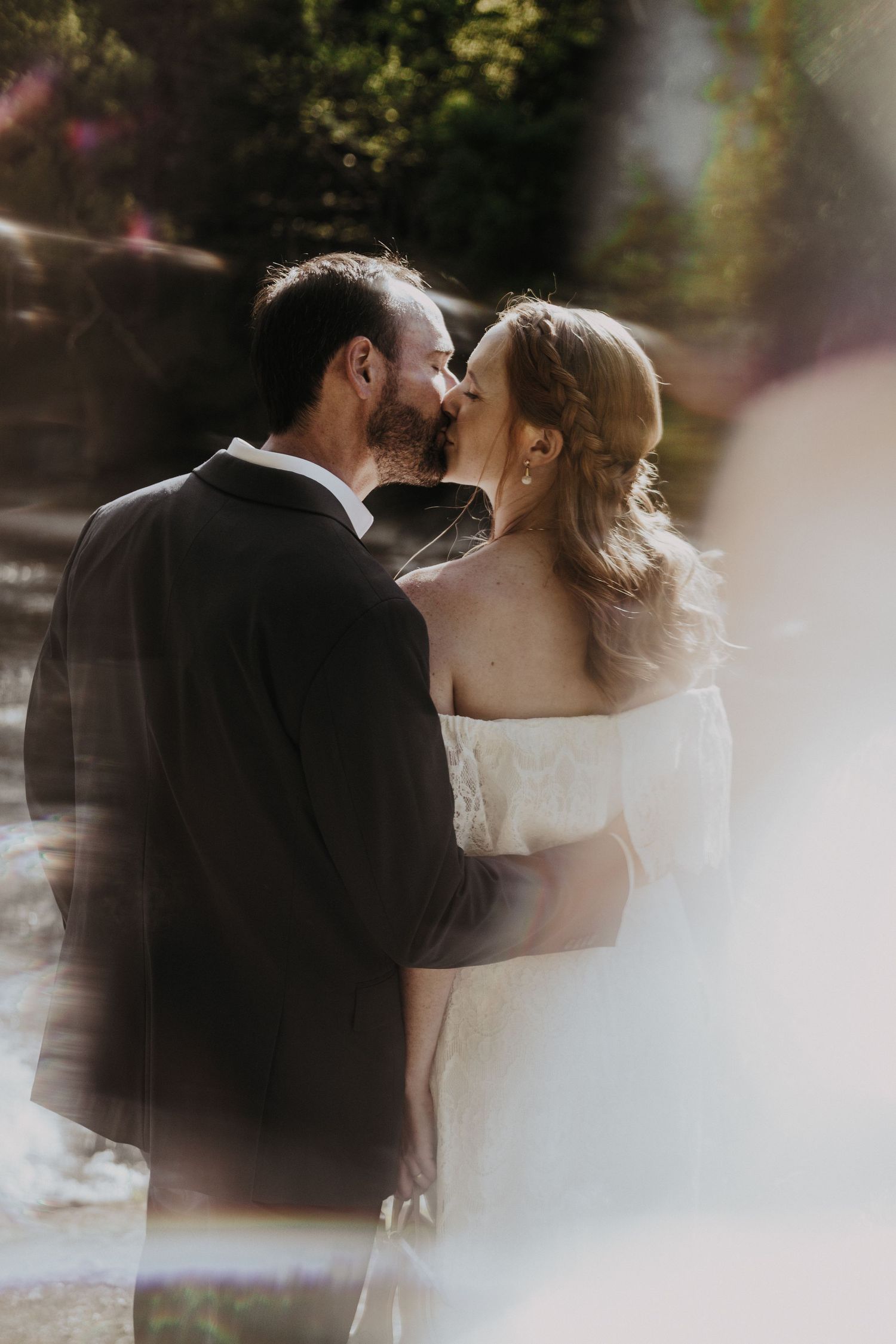 Intimate moment captured in soft sunlight with dreamy lens flare.