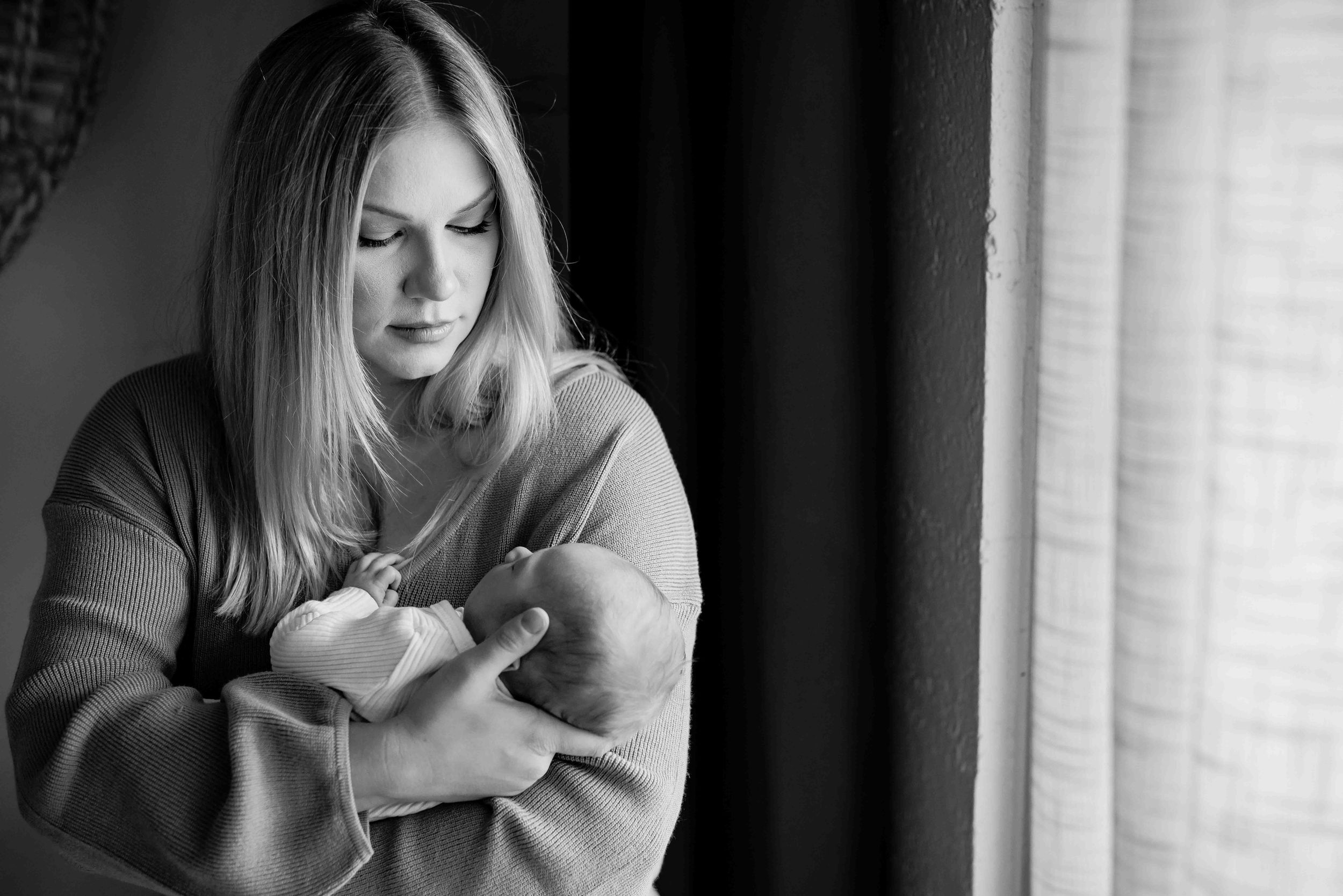 Black-and-white portrait of a new mother in soft window light during a Mountain Home newborn session
