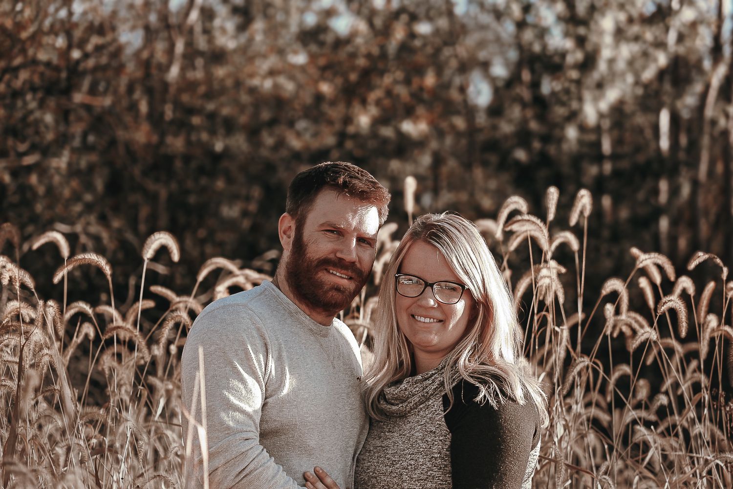 A cozy autumn portrait amidst golden cattails in a natural field setting.