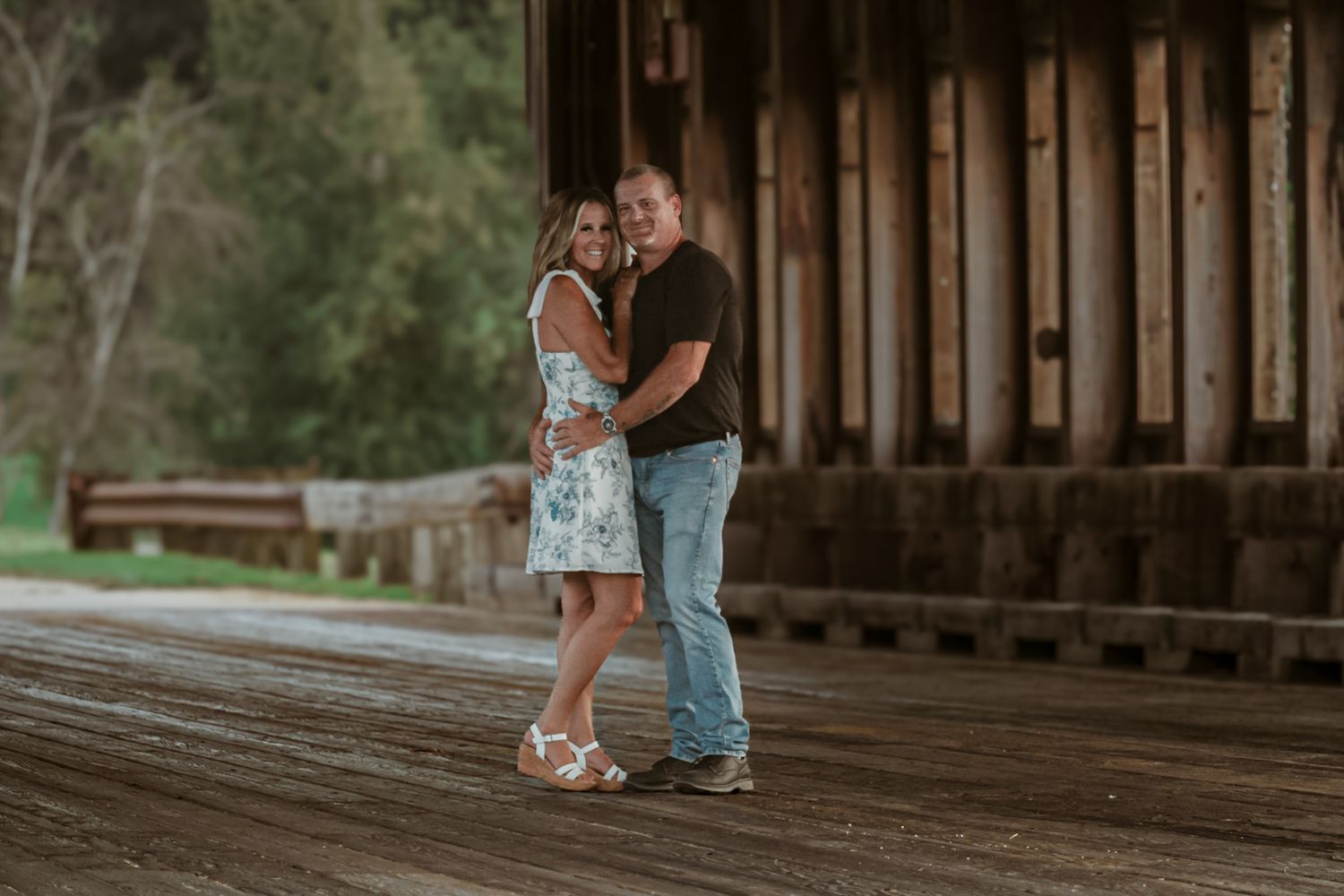 Romantic moments captured on a rustic wooden bridge walkway.