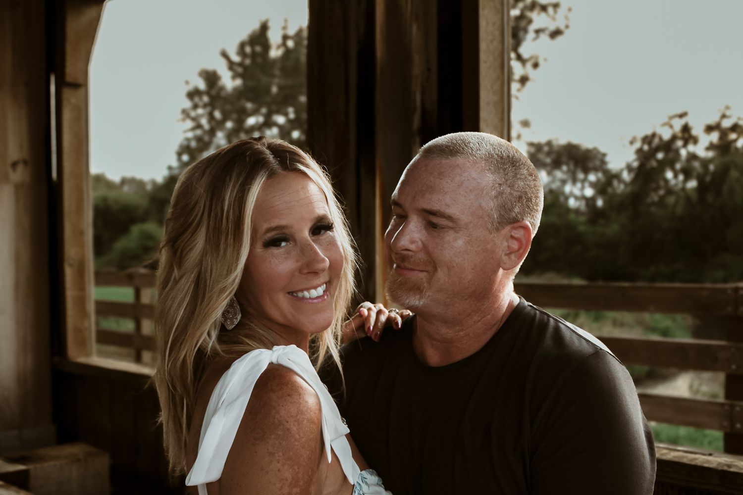 Loving couple shares intimate moment on rustic wooden porch during golden hour.