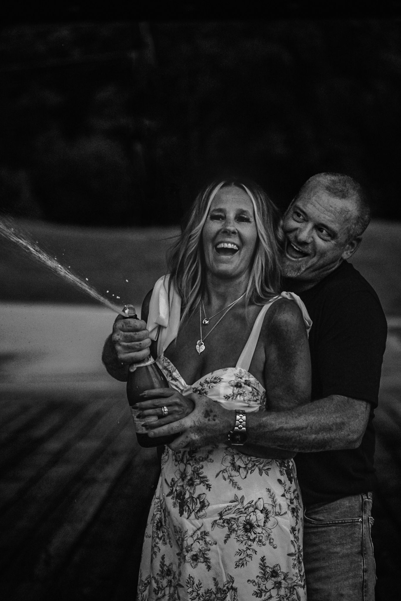 Black and white photo of couple laughing and embracing in casual attire.
