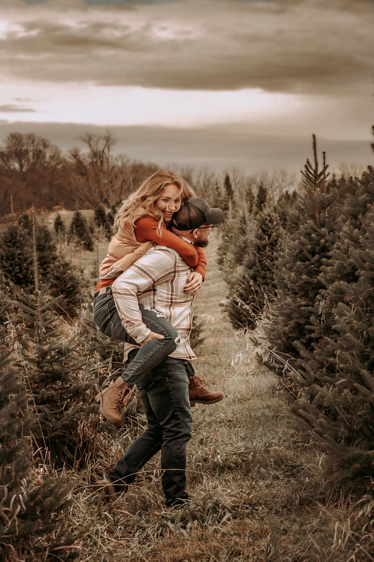 Romantic moment between couple in casual wear among evergreen trees at sunset.