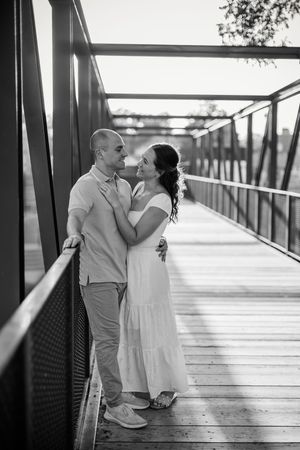 A romantic black and white photo series of a couple in white attire sharing intimate moments on a wooden boardwalk.