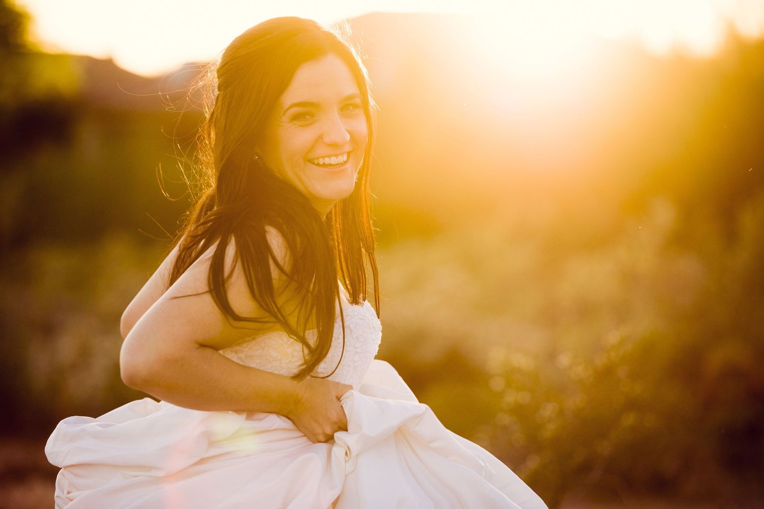Photo of Cat McKenna in white dress laughing at sunset