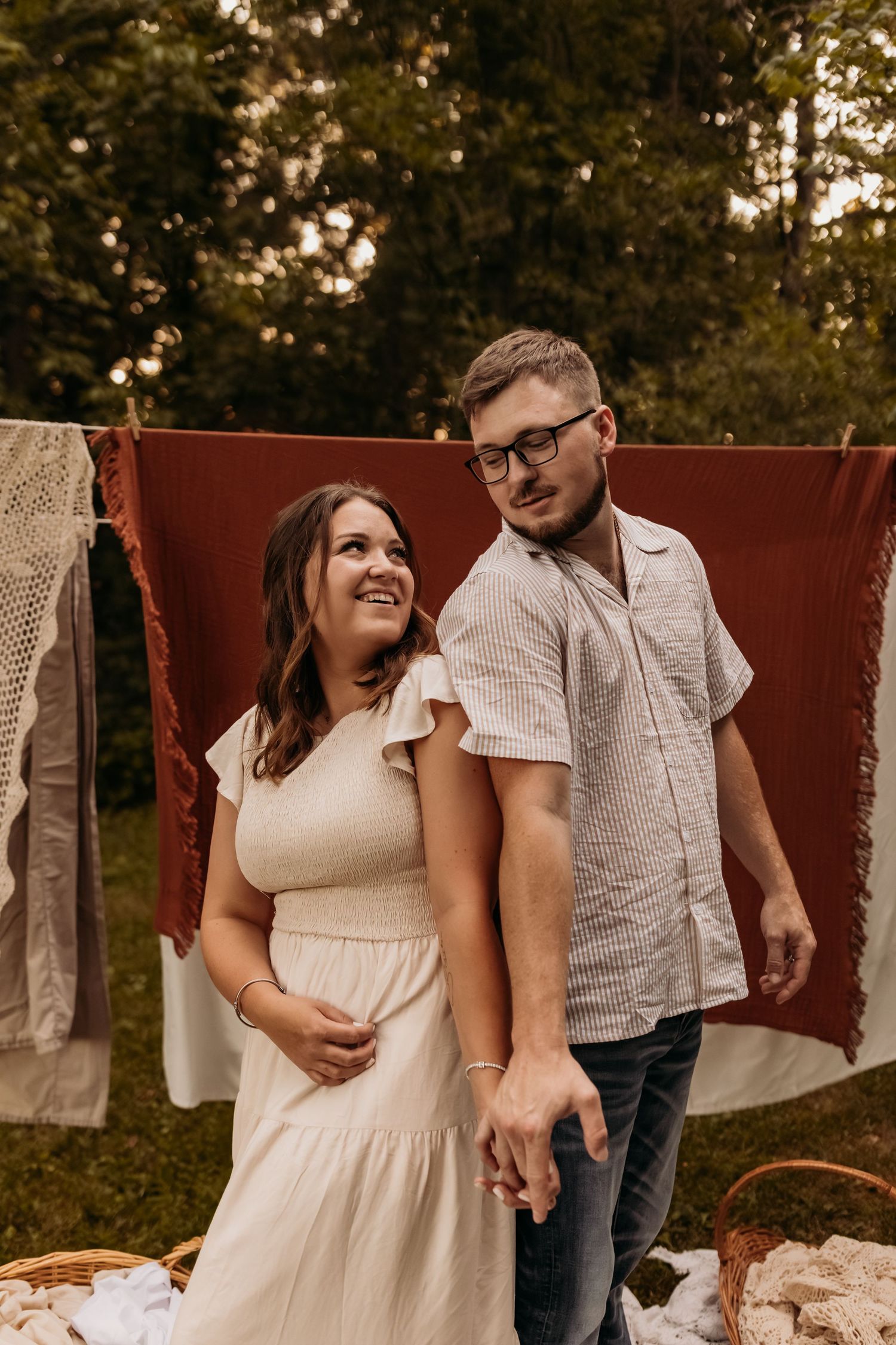 Couple standing in front of hanging textiles during outdoor photoshoot.