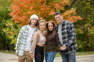 Group walking together on a path surrounded by vibrant autumn foliage and trees.