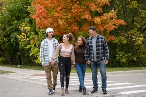 People strolling down a walkway with beautiful fall colors in the background.